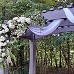 Outdoor wedding arbor decorated in white, cream, ivory roses by Atlanta florist